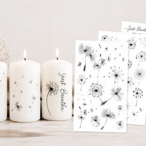 Può includere: Tre candele a colonna bianche con stoppini accesi, decorate con illustrazioni di denti di leone neri. Una candela riporta la scritta "Just Breathe". Accanto si trovano tre fogli rettangolari di adesivi con denti di leone e le scritte "Just Breathe" e "Make Wish".