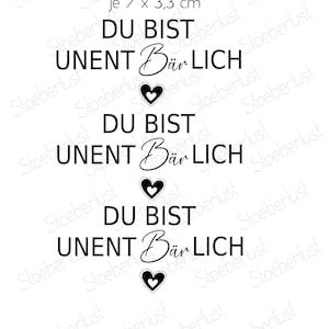 Op de afbeelding: Witte wrijf-op transfers met zwarte tekst en hartontwerpen. De tekst luidt "DU BIST UNENT Bär LICH" driemaal herhaald, waarbij elk geval vergezeld gaat van een hart. Elke transfer meet ongeveer 7 x 3,3 cm.