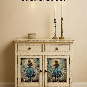 Op de afbeelding: Een wit, verweerd dressoir met twee lades en twee deuren. De deuren hebben een kleurrijke illustratie van een meisje in een blauwe jurk. Twee messing kandelaars met brandende kaarsen en een kleine decoratieve pot staan bovenop.