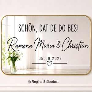 May include: A rectangular mirror with a thin gold frame featuring black text that reads SCH&Ouml;N, DAT DE DO BES!, Ramona Maria & Christian, and the date 05.09.2026 with a small heart icon centered below the date.