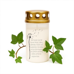 Peut inclure: Une bougie cylindrique avec un couvercle doré et une illustration de pissenlit. La bougie porte du texte en allemand. Des vignes de lierre vert avec des feuilles sont disposées autour de la bougie.