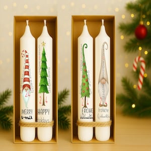 Puede incluir: Dos velas de adviento blancas en una caja, cada una con un diseño festivo. Una vela presenta un gnomo a rayas rojas y blancas, la otra un árbol de Navidad verde. El texto incluye "MERRY X-mas" y "HAPPY Holidays".