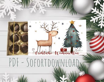 May include: A Christmas-themed card with a watercolor illustration of a reindeer and a decorated Christmas tree. The card has the text "Fröhliche Weihnachten" and is surrounded by Christmas ornaments and snowflakes. A box of chocolates is on the left.