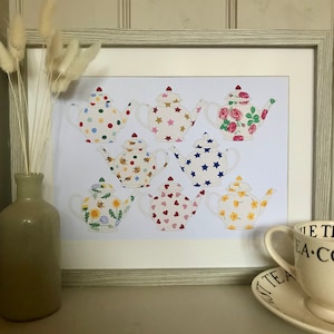 以下が含まれることがあります： 星、蜂、花、ハートなど、さまざまな模様が描かれたカラフルなティーポット8個がフレームに入ったプリント。ティーポットは白い背景にグリッド状に配置されています。