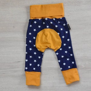 May include: Blue and yellow baby leggings with a white star pattern. The leggings have a yellow waistband and cuffs.