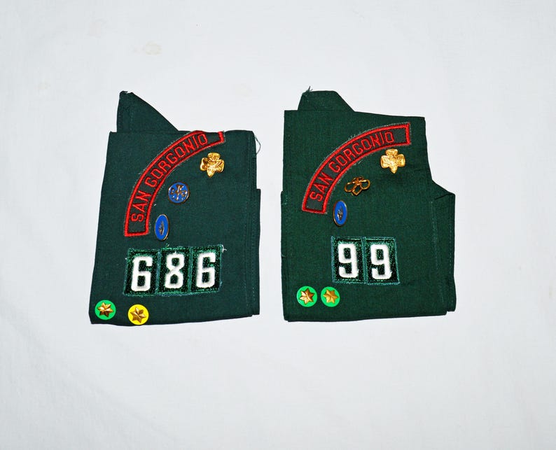 May include: Two green fabric patches with embroidered text "SAN GORGONIO" and numbers "686" and "99". The patches have gold and blue pins attached.