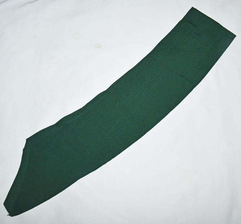 May include: A dark green fabric sash, often used for scouting or other organisations.