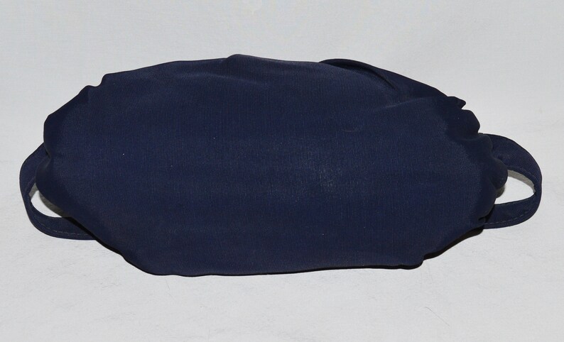 May include: A dark blue fabric pouch with two handles. The pouch is folded and appears to be empty.