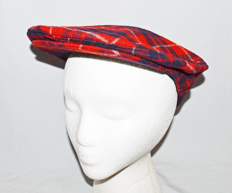 Puede incluir: Gorra plana a cuadros rojos, azules y blancos. La gorra est&aacute; hecha de una tela suave y tiene un dise&ntilde;o cl&aacute;sico. El sombrero se muestra en una cabeza de maniqu&iacute; blanca.