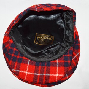Puede incluir: Gorra de estilo newsboy a cuadros rojos, blancos y azul marino. El interior est&aacute; forrado con sat&eacute;n negro y presenta una etiqueta dorada que dice "Pendleton". Un estilo cl&aacute;sico, adecuado para diversas ocasiones.