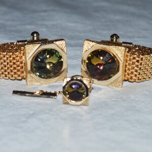 May include: A set of gold cufflinks and a tie tack with iridescent green and brown stones.