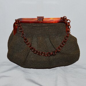 May include: A brown woven purse with a tortoise shell frame and a chain strap.
