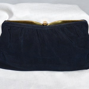 May include: A black fabric clutch purse with a gold metal clasp.