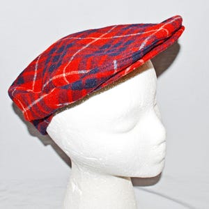 Puede incluir: Gorra plana a cuadros rojos, azules y blancos. La gorra est&aacute; hecha de tela tejida y tiene una forma cl&aacute;sica y redondeada con una peque&ntilde;a visera. El patr&oacute;n de cuadros presenta una base roja audaz con l&iacute;neas azules y blancas.