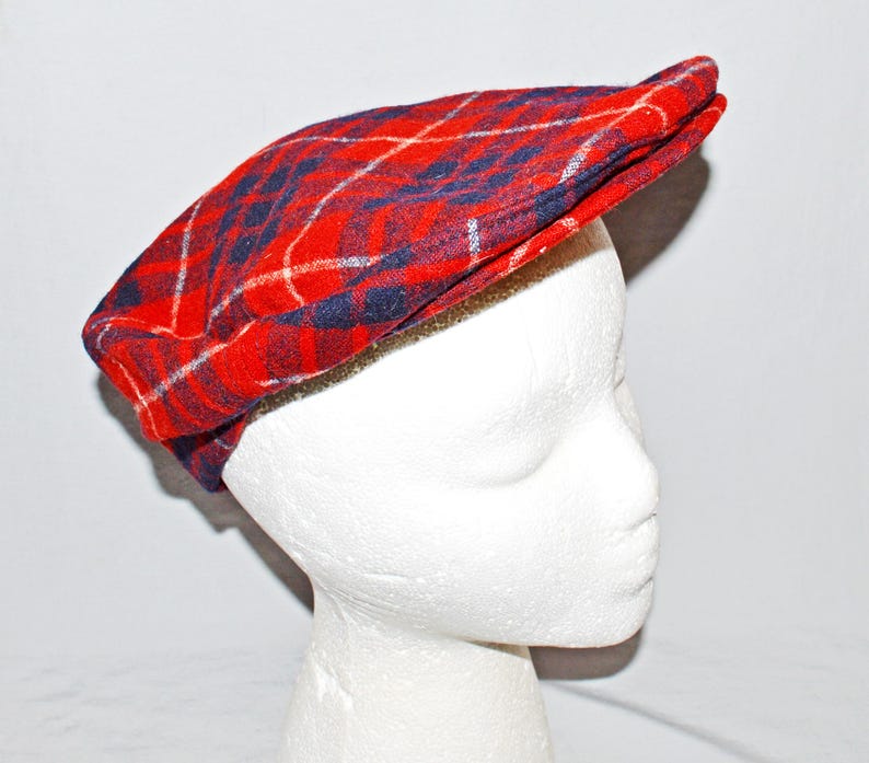 Puede incluir: Gorra plana a cuadros rojos, azules y blancos. La gorra est&aacute; hecha de tela tejida y tiene una forma cl&aacute;sica y redondeada con una peque&ntilde;a visera. El patr&oacute;n de cuadros presenta una base roja audaz con l&iacute;neas azules y blancas.