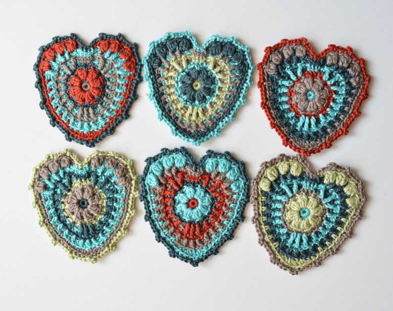 Puede incluir: Seis posavasos de coraz&oacute;n hechos a crochet en varios colores, incluyendo turquesa, verde, marr&oacute;n y rojo. Los posavasos tienen un dise&ntilde;o circular en el centro.