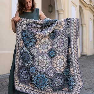 May include: A large, rectangular crochet blanket featuring a complex pattern of interconnected hexagonal motifs. The design incorporates shades of deep blue, slate gray, soft lavender, and cream, with intricate floral-inspired textures.