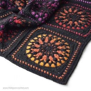 May include: Close-up of a black crochet blanket with a colorful mandala design. The blanket is made with a variety of colors, including red, orange, yellow, and purple. The mandala design is intricate and detailed, and the blanket is soft and cozy.