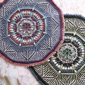 Puede incluir: Dos tapetes de ganchillo hechos a mano. Uno es principalmente morado, con detalles turquesa, rosa y crema. El otro es blanco y negro con detalles turquesa y crema. Ambos tienen patrones geométricos intrincados.