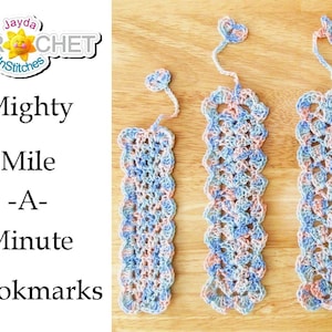 Può includere: Cinque segnalibri all'uncinetto di diverse lunghezze, con un delicato motivo floreale rosa e blu. I segnalibri sono etichettati "Mighty Mile -A- Minute Bookmarks".