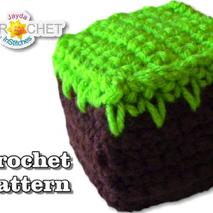 May include: Crocheted Minecraft block with a brown base and a green grass top. The block is a toy and is made with yarn. The image includes the text "Crochet Pattern".