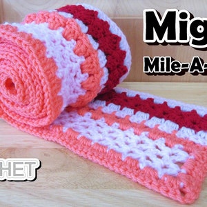 May include: A crocheted scarf in shades of pink, white, and red. The scarf is rolled up and has a label that says "Jayda Crochet InStitches". The text "Mighty Mile-A-Minute" is also visible in the image.
