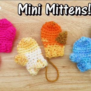 May include: Four pairs of mini crocheted mittens in different colours: pink, yellow and white, orange and brown, and blue. The mittens are laid out on a wooden surface.