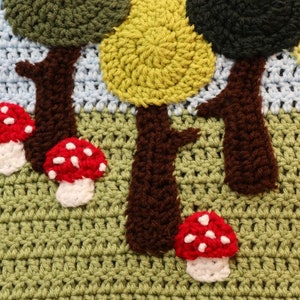 May include: Crocheted forest scene with brown trees, green and yellow leaves, and red and white mushrooms.