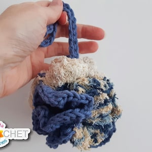 May include: A blue and white crocheted bath pouf with a loop handle. The pouf is made with a combination of cotton and recycled denim fabric.