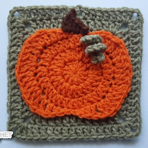 May include: A crocheted pumpkin applique in orange, with a brown stem and green accents, sits on a square of olive green crochet. The pumpkin is centered on the square, creating a fall-themed design.