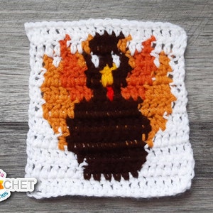 May include: Crocheted square featuring a brown turkey with orange and yellow feathers. The turkey is centered on a white crocheted background.