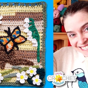 May include: A crocheted square featuring a butterfly, flowers, and a tree trunk. The square is framed with a green border. The background shows a woman smiling and holding her chin.