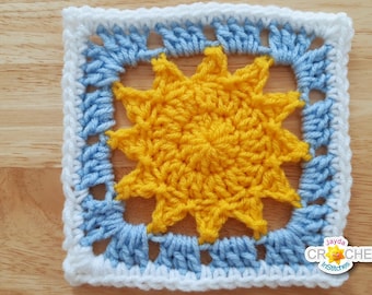 May include: A crocheted square with a yellow sun design in the center. The sun is surrounded by a blue border and a white outer border.