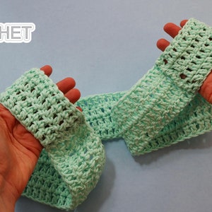 May include: A light green crocheted headband, held in two hands. The headband is made with a simple stitch pattern and has a slightly textured look.