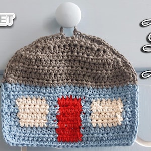 May include: A crocheted gray, blue, white, and red house-shaped pot holder with the text "Home Sweet Home" on a blue background.