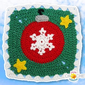 May include: A green crochet square featuring a red and white bauble in the centre. The bauble has a snowflake design and is surrounded by two yellow stars. The square has a white border with a scalloped edge.