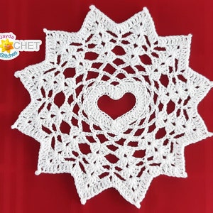 May include: White crochet doily with a heart-shaped hole in the center. The doily is on a red background.
