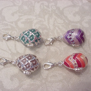 May include: Four silver charm pendants shaped like eggs with different colored enamel designs. Each egg has a silver clasp.