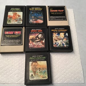 May include: A collection of Atari video game cartridges, including "Football," "Slot Racers," "Mouse Trap," "Donkey Kong," "Space War," "Missile Command," and "Pele's Soccer." The cartridges are black with colorful game art labels.