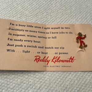 May include: Vintage Reddy Kilowatt advertisement with a pin. The tan paper has a poem about electricity and the Reddy Kilowatt logo in red. A small pin of Reddy Kilowatt in red and gold is attached.