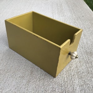 May include: A yellow wooden box with a white ceramic knob. The box is empty and has a distressed finish.