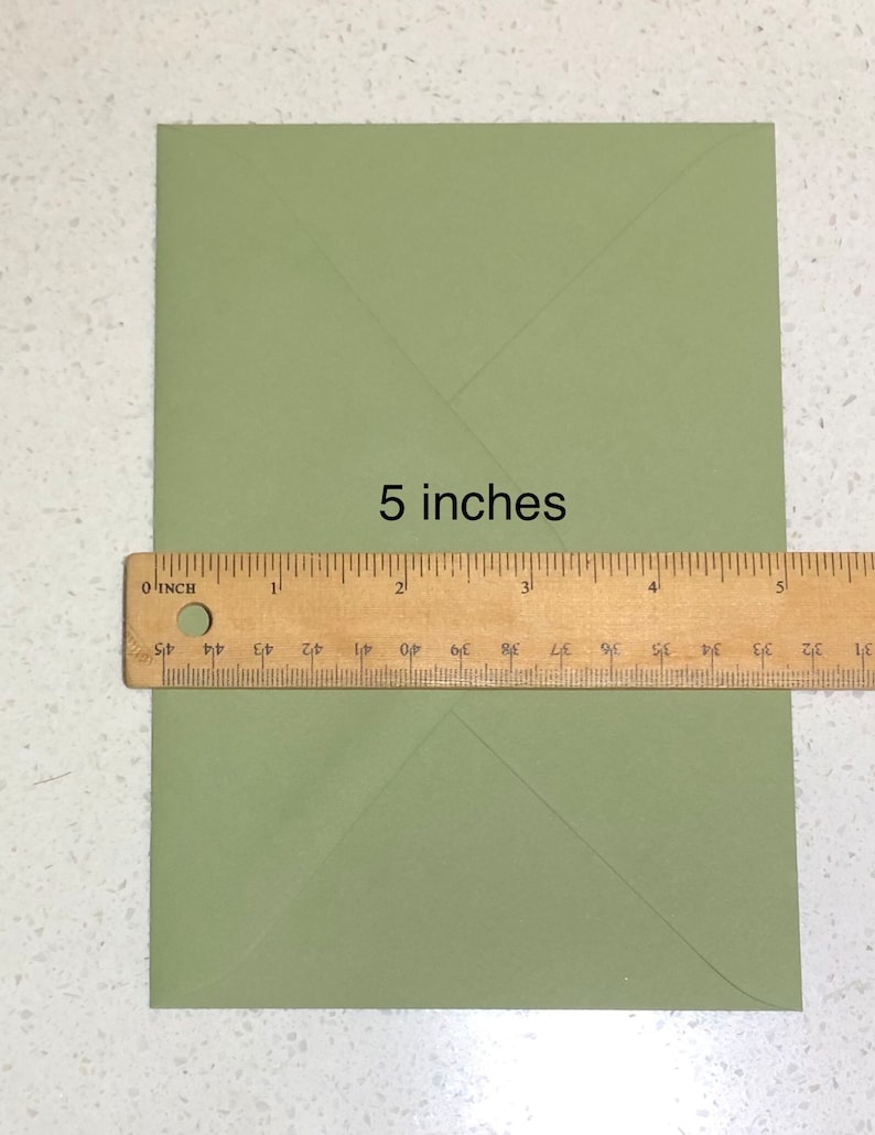May include: A green envelope measuring 5 inches in length. The envelope is folded in half and has a crease down the center.