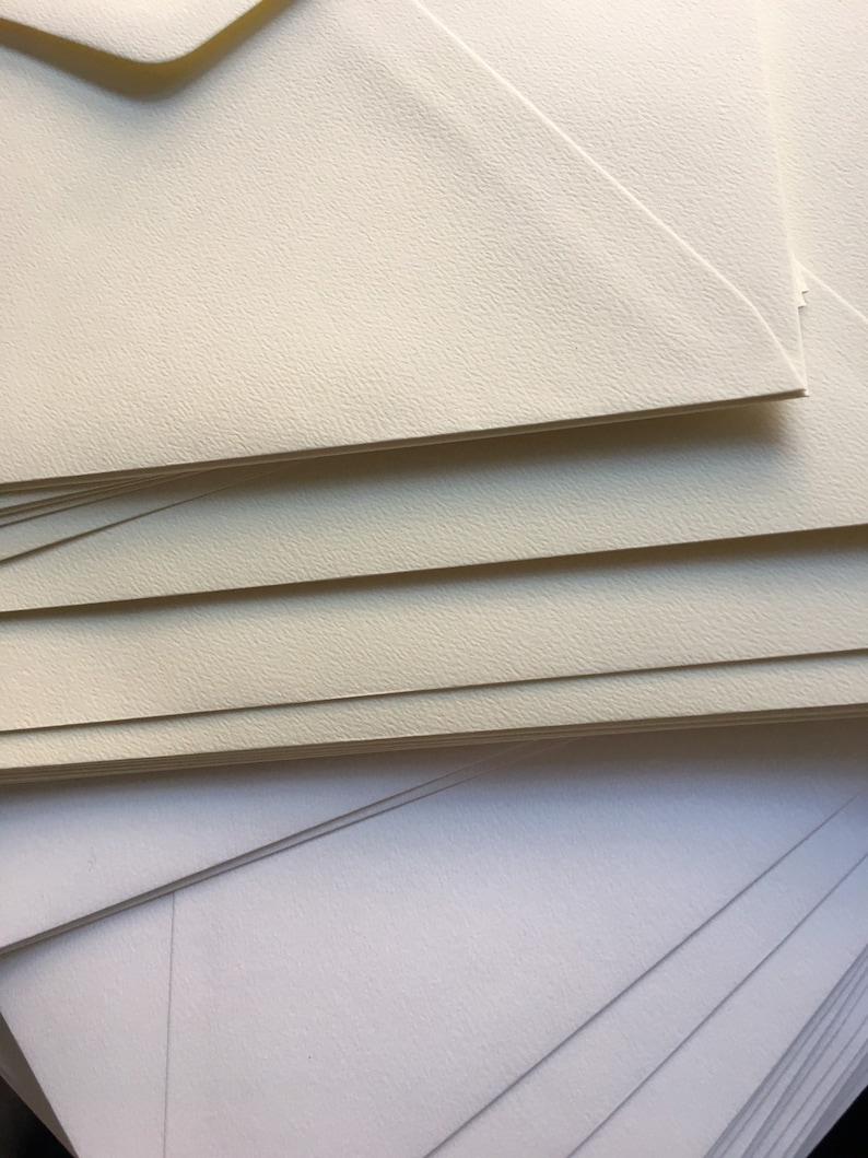Op de afbeelding: Een stapel ivoren enveloppen met daaronder een stapel witte enveloppen.