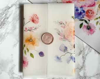 May include: A floral invitation suite featuring watercolor flowers in pink, peach, yellow, and blue. The invitation is sealed with a rose gold wax seal. Additional floral stationery is visible in the background.