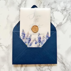May include: A navy blue invitation suite featuring a floral design with blue and purple flowers. The invitation is inside a navy blue envelope. The invitation has the text "Save the Date" and "January 15, 2025". A gold wax seal is on the invitation.