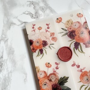 May include: A white envelope with a floral design in shades of orange, pink, and burgundy. The envelope has a red wax seal with the text "Just Do You" in white.