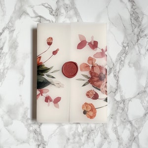 May include: A white envelope with a floral design in shades of pink and red. The envelope has a red wax seal with the initials "J & B" embossed on it.