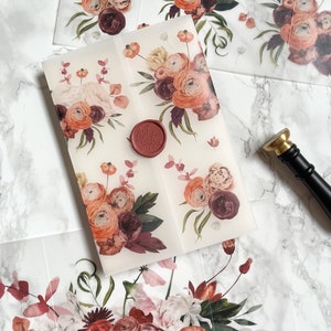 May include: A set of four translucent envelopes with a floral design in shades of orange, pink, and burgundy. The envelopes are sealed with a red wax seal.