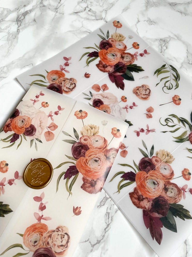 May include: Two sheets of clear vellum paper with a floral design. The design features a bouquet of burgundy, peach, and cream flowers with green leaves. The sheets are perfect for crafting, scrapbooking, or adding a touch of elegance to any project.