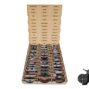 May include: A wooden game organiser with multiple compartments for cards and game pieces. The organiser has labelled sections with text, including "Ancient Artifacts" and "Black Bear." A silhouette of a Viking with a shield and axe is in the corner.